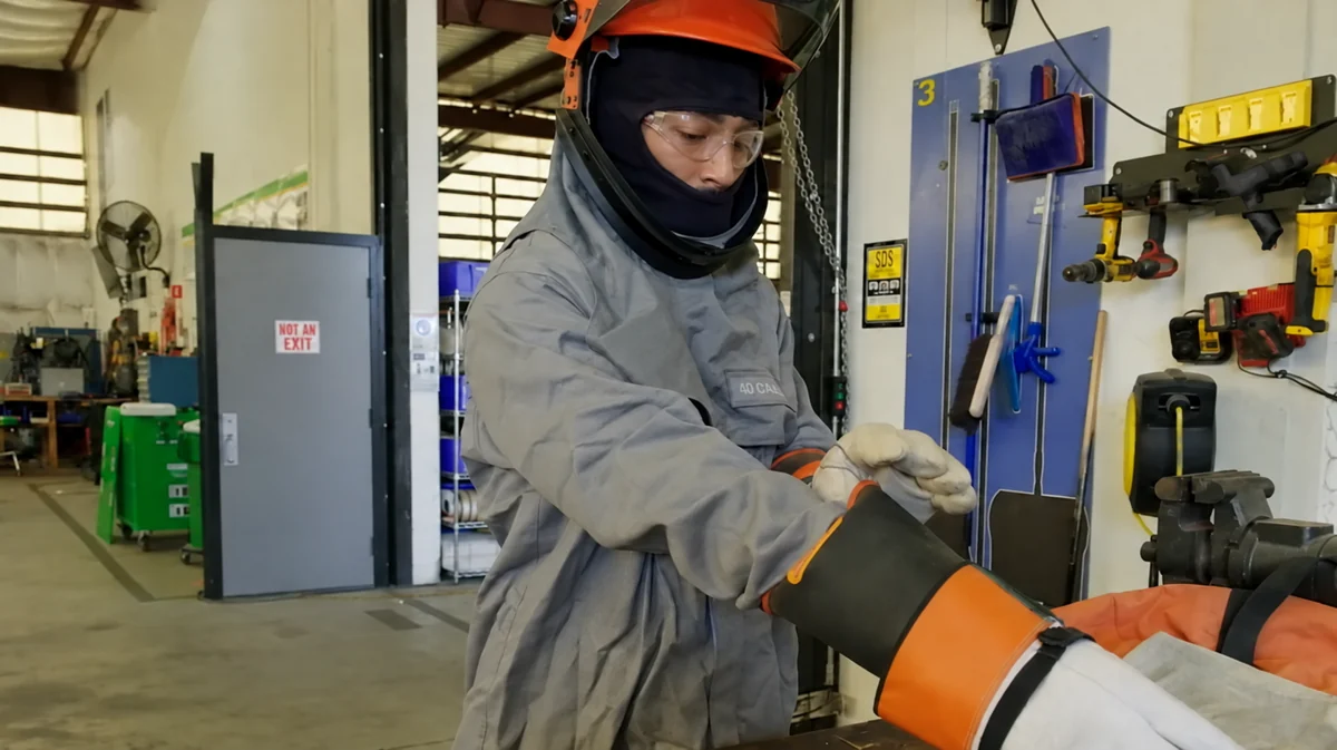 Technician putting on protective gloves in an equipment repair workshop